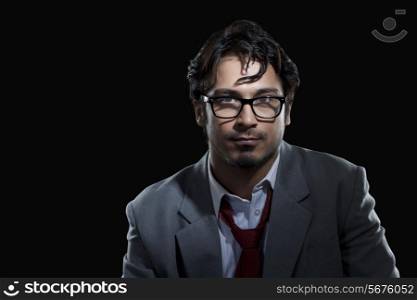 Portrait of young businessman wearing glasses over black background