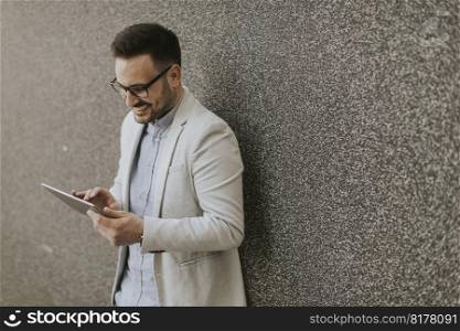 Portrait of young businessman with digital tablet standing outdoor