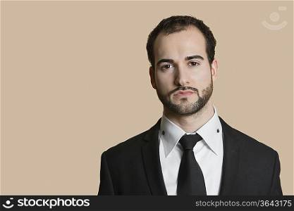 Portrait of young businessman with short hair and beard over colored background