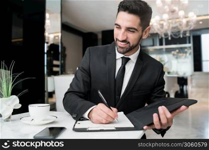 Portrait of young businessman working at the hotel lobby. Business travel concept.