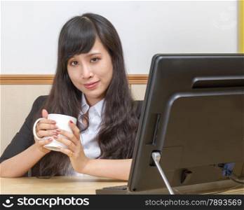 portrait of young businesswoman drinking coffee at desk