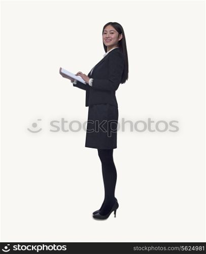 Portrait of young businesswoman holding a digital tablet, looking at camera, full length, studio shot