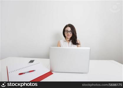 Portrait of young businesswoman in nerd glasses with laptop at desk in office