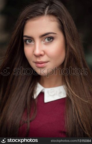 Portrait of young businesswoman in raspberry jacket with white collar.