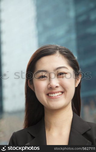 Portrait of young businesswoman outdoors among skyscrapers