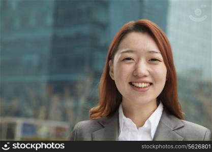 Portrait of young businesswoman outdoors among skyscrapers, close-up