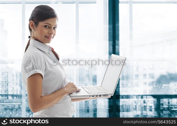 Portrait of young businesswoman smiling with laptop at office