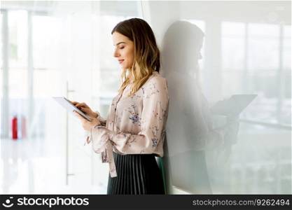Portrait of young businesswoman standing with digital tablet in office