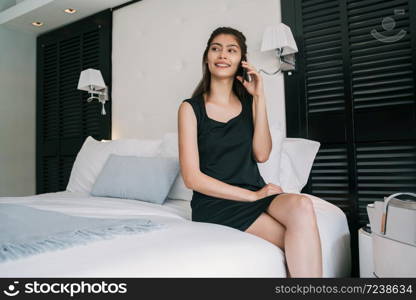 Portrait of young businesswoman talking on the phone at the hotel room. Business travel concept.