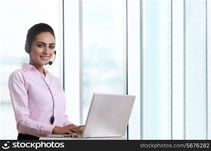 Portrait of young businesswoman using headset and laptop at office