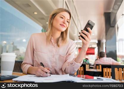 Portrait of young businesswoman using her mobile phone while working at coffee shop.coffee shop. Business concept.
