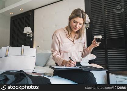 Portrait of young businesswoman working at the hotel room. Business travel concept.
