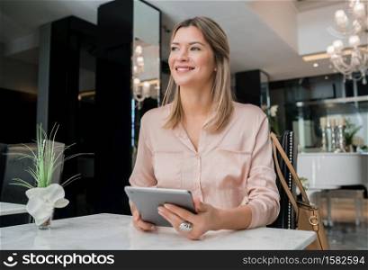 Portrait of young businesswoman working on her digital tablet at hotel lobby. Business travel concept.