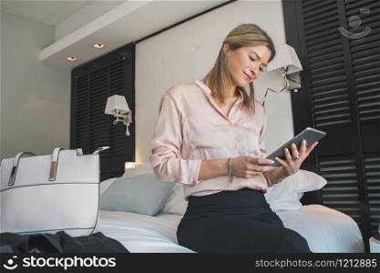 Portrait of young businesswoman working on her digital tablet at the hotel room. Business travel concept.