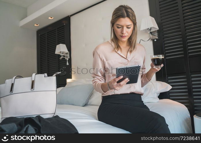 Portrait of young businesswoman working on her digital tablet at the hotel room. Business travel concept.