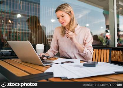 Portrait of young businesswoman working on her laptop at a coffee shop. Business concept.