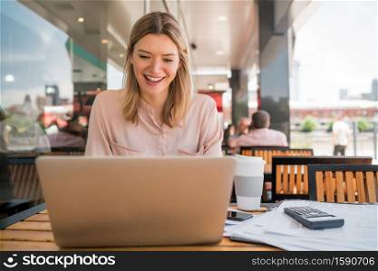 Portrait of young businesswoman working on her laptop at a coffee shop. Business concept.