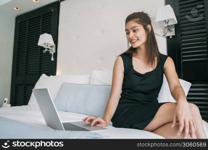 Portrait of young businesswoman working on her laptop at the hotel room. Business travel concept.