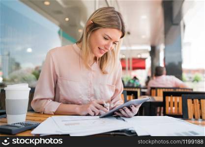 Portrait of young businesswoman working with a digital tablet at coffee shop. Business concept.