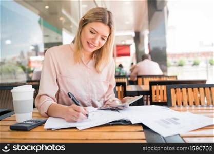 Portrait of young businesswoman working with a digital tablet at coffee shop. Business concept.