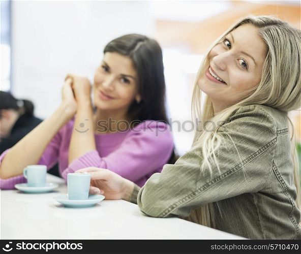 Portrait of young businesswomen smiling at cafeteria table