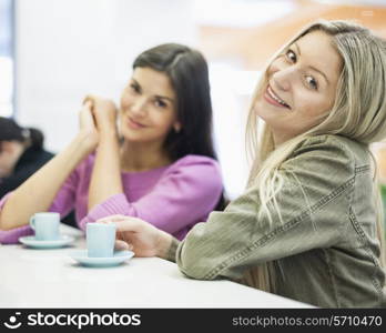 Portrait of young businesswomen smiling at cafeteria table