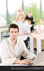 Portrait of young casual business student with team in back