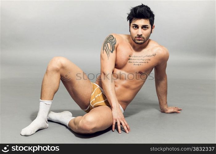 Portrait of young caucasian man with underwear posing over grey background
