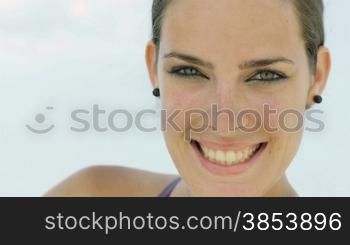Portrait of young caucasian woman looking at camera near the sea. Head and shoulders, copy space
