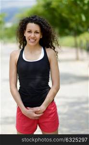 Portrait of young cheerful smiling woman in sports wear in urban background
