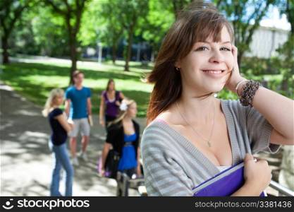 Portrait of young college girl smiling with friends in background