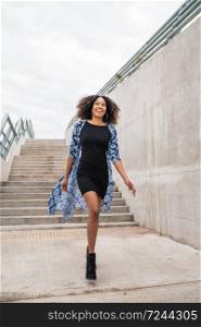 Portrait of young confident afro american woman walking on stairs outdoors.