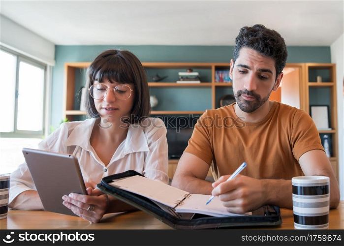 Portrait of young couple calculating and paying bills on digital tablet from home. Couple planning monthly budget.