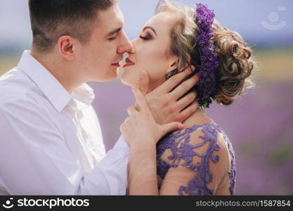 portrait of Young couple in love kissing in a lavender field on summer. girl in a luxurious purple dress.. portrait of Young couple in love kissing in a lavender field on summer. girl in a luxurious purple dress