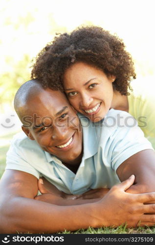 Portrait Of Young Couple Laying On Grass In Park