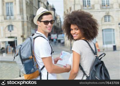portrait of young couple of tourists with map in city