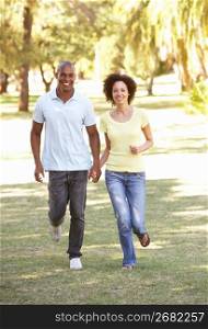 Portrait Of Young Couple Running Through Park