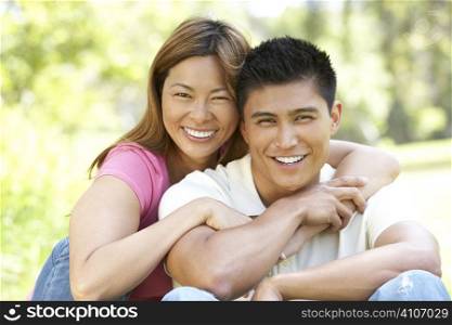 Portrait Of Young Couple Sitting In Park
