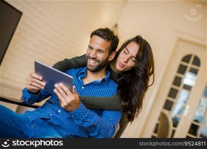 Portrait of young couple sitting in the living room and using digital tablet