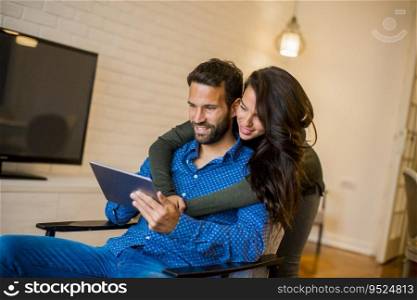 Portrait of young couple sitting in the living room and using digital tablet