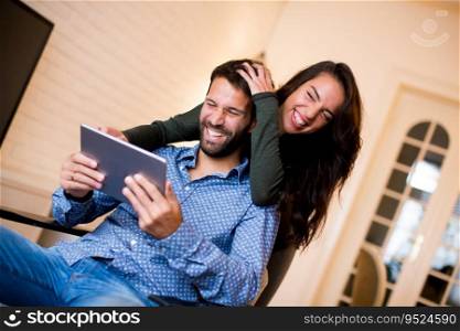 Portrait of young couple sitting in the living room and using tablet