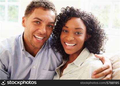 Portrait Of Young Couple Sitting On Sofa At Home