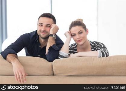 Portrait of young couple sitting on sofa in modern white apartment