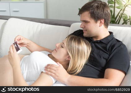 Portrait of young couple waiting for baby looking on fetus ultrasound scan