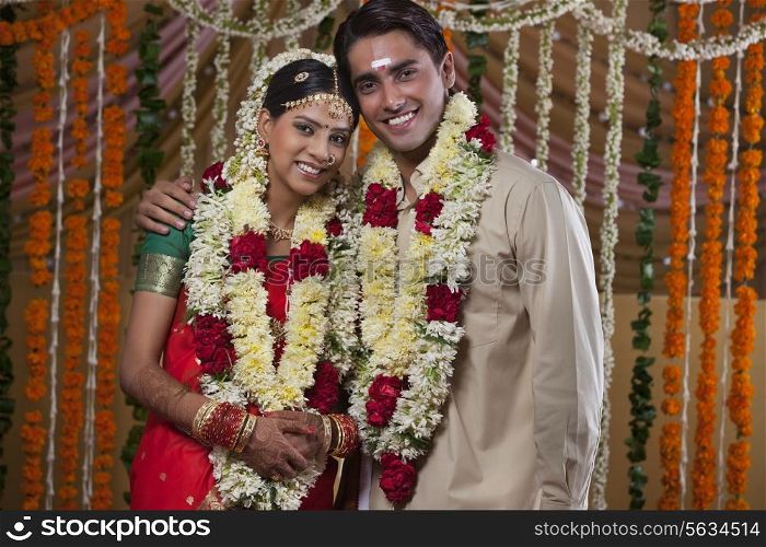 Portrait of young couple wearing garlands during traditional Indian wedding