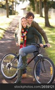 Portrait Of Young Couple With Cycle In Autumn Park