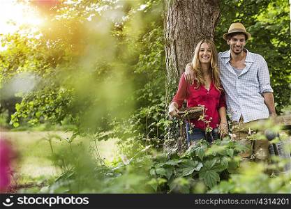 Portrait of young couple with flower basket in garden