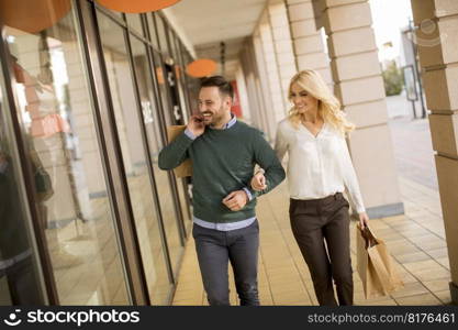 Portrait of young couple with paper shopping bags in city