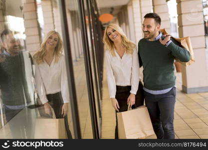 Portrait of young couple with paper shopping bags in city