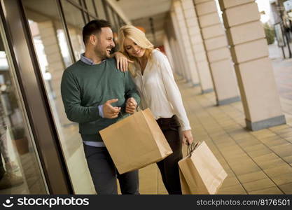 Portrait of young couple with paper shopping bags in city